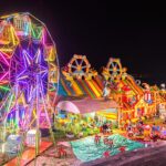 Illuminated Ferris Wheel, Bouncing Castle And Carousel At Night In A Funfair In Vientiane, Laos